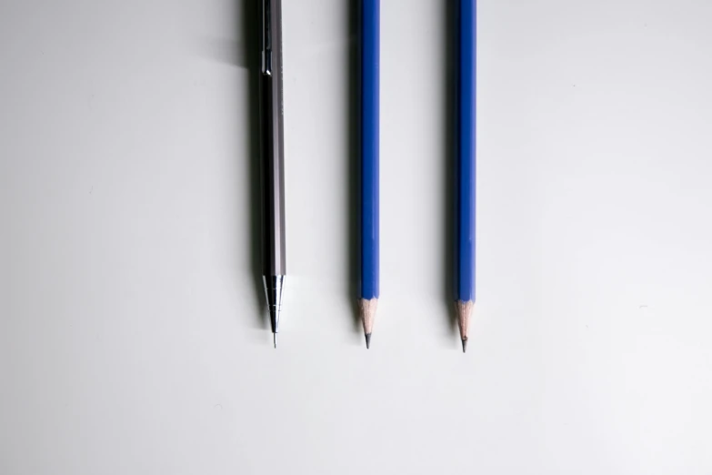 two pencils sitting next to each other on a table, a stipple, by Carey Morris, unsplash, hyperrealism, blue silver and black, three fourths view, set against a white background, ocd