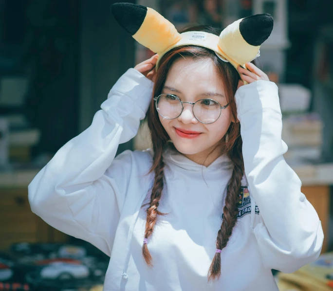 a woman wearing a pikachu hat and glasses, a cartoon, inspired by Kim Jeong-hui, trending on pexels, two pigtails hairstyle, white fox ears, wearing sweatshirt, photography]