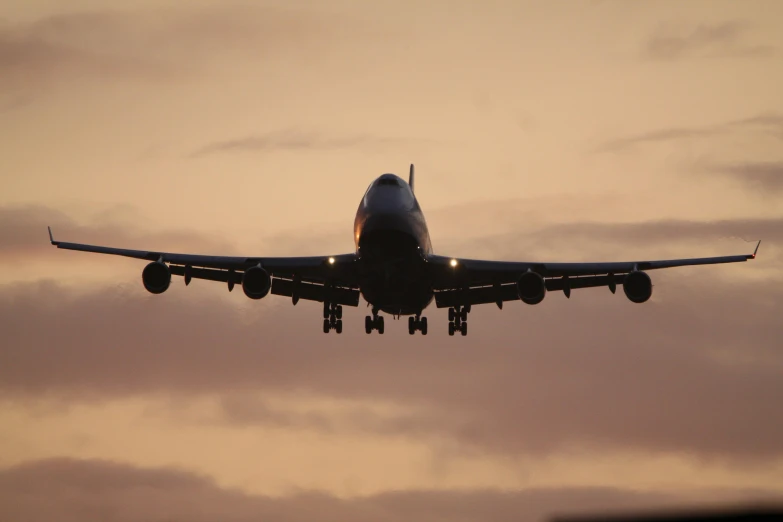 a large jetliner flying through a cloudy sky, by Paul Bird, pexels contest winner, landing gear, evening sunlight, where a large, front on