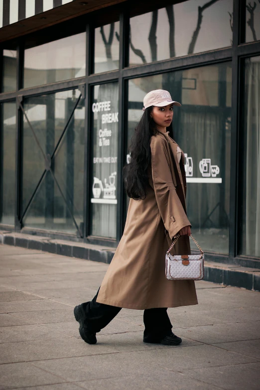 a woman walking down a sidewalk carrying a purse, inspired by Wang E, trending on pexels, wearing a long coat, jakarta, tall hat, cardboard
