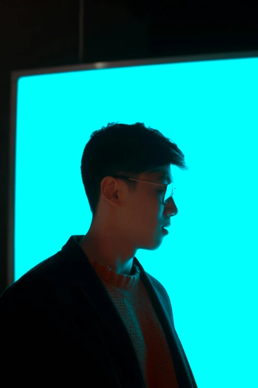 a man standing in front of a blue screen, an album cover, inspired by Russell Dongjun Lu, pexels contest winner, aestheticism, teal lighting, profile shot, indoor picture, dark shades