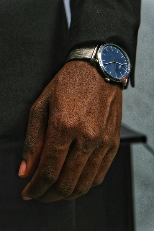 a close up of a person wearing a watch, inspired by Gerard Sekoto, photorealism, wearing dark blue suit, gun metal grey, thumbnail, dark skinned