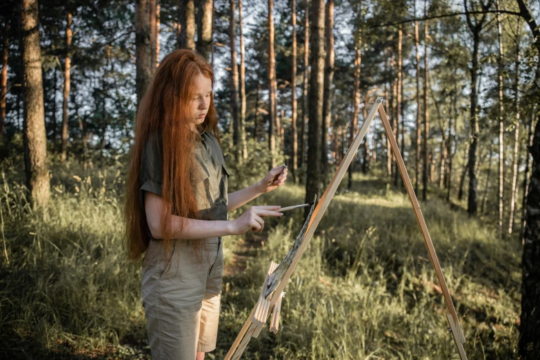 a woman standing in the woods using a cell phone, an oil painting, by Grytė Pintukaitė, pexels contest winner, plein air, drawing an arrow from his quiver, red haired young woman, stands at a his easel, portrait of forest gog