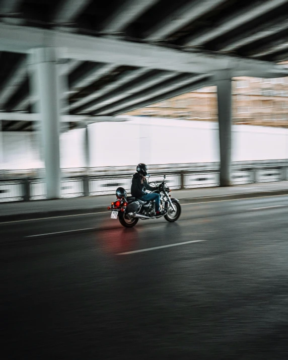 a man riding on the back of a motorcycle down a street, overpass, 🚿🗝📝, unsplash 4k, non-binary