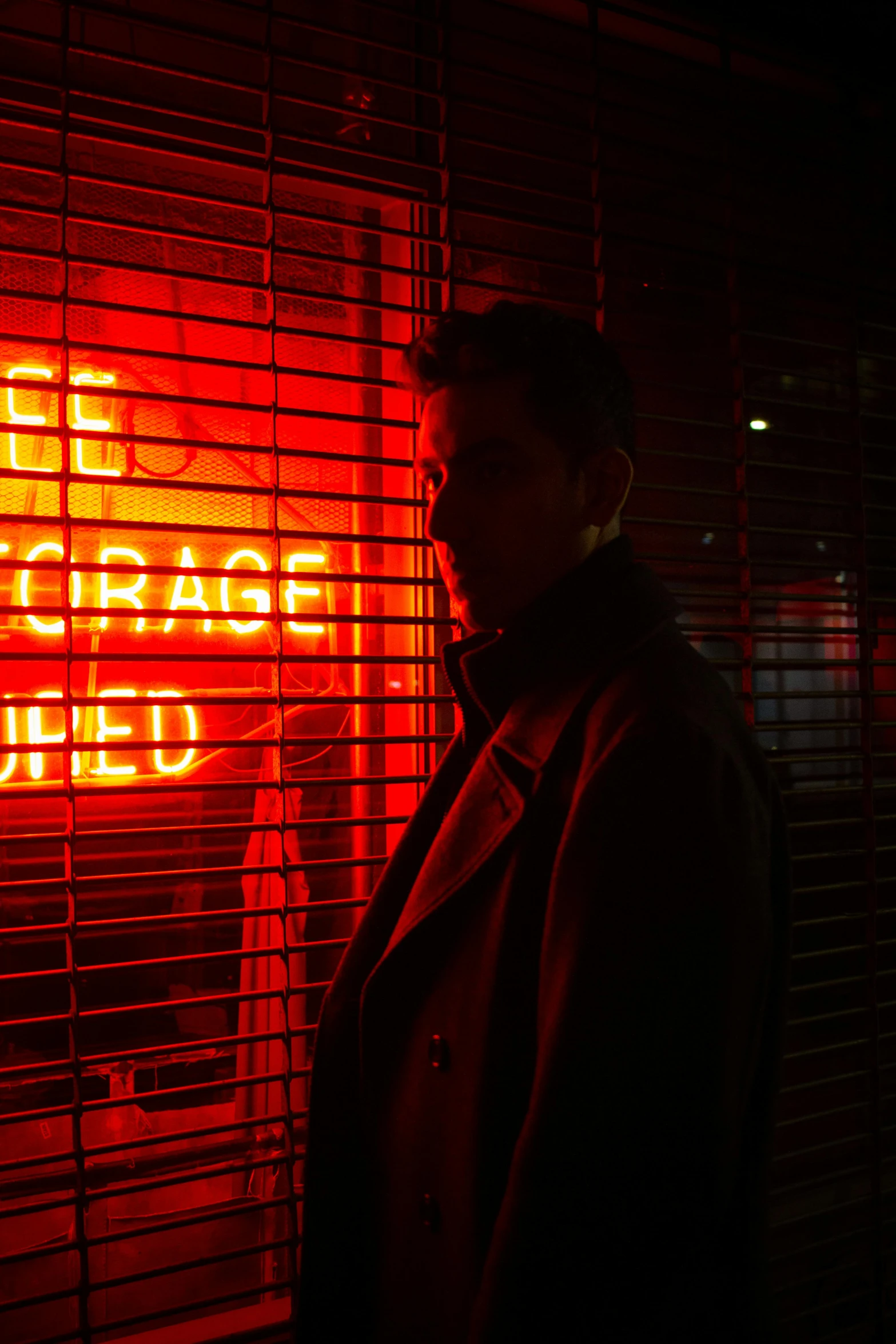 a man standing in front of a neon sign, inspired by Nan Goldin, unsplash, bauhaus, colin farrell, cage, red light, david gandy