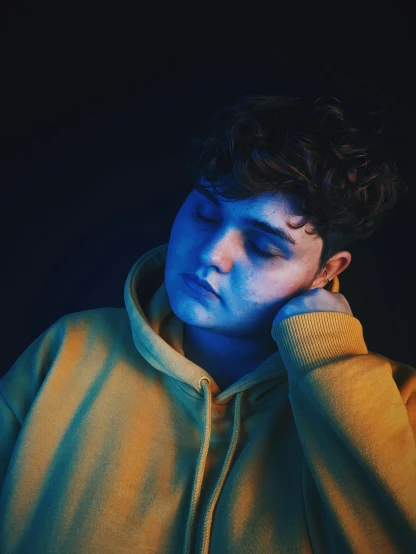 a close up of a person in a hoodie, an album cover, inspired by Elsa Bleda, trending on pexels, realism, overweight!! teenage boy, yellow and blue, non-binary, sadness look
