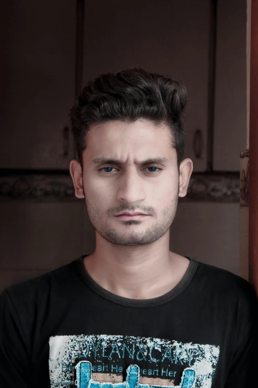 a man in a black shirt posing for a picture, a colorized photo, by Ismail Acar, trending on reddit, piercing stare, nepal, non binary model, spiky