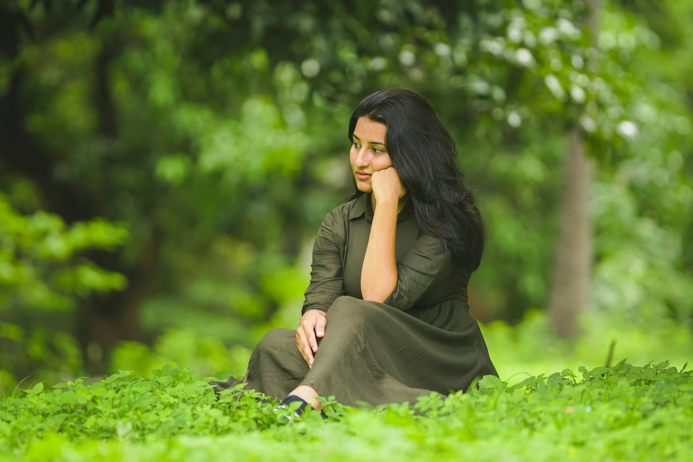 a woman sitting on top of a lush green field, an album cover, pexels contest winner, hurufiyya, thoughtful expression, aketan, casual green clothing, 15081959 21121991 01012000 4k