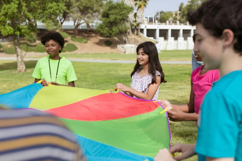 a group of young people sitting on top of a lush green field, pexels contest winner, american barbizon school, kites, multi - coloured, casual playrix games, still of rainbow ophanim