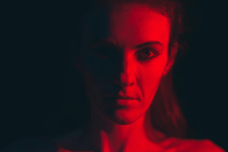 a woman with a red light on her face, by Adam Marczyński, pexels contest winner, digital art, carice van houten, intimidating stare, psychological horror movie still, volumetric lighting. red