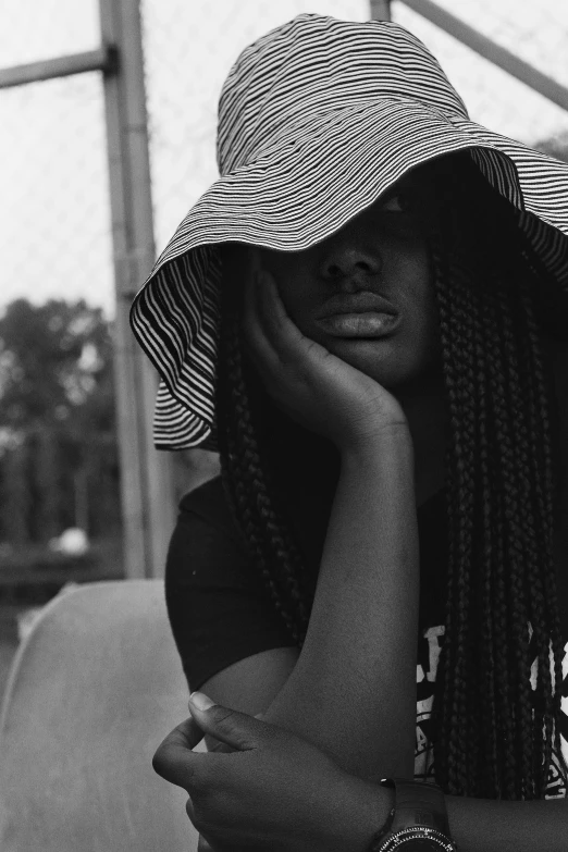 a black and white photo of a woman wearing a hat, by Dulah Marie Evans, hip hop aesthetic, long braids, lemonade, sadness personified