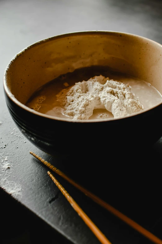 a bowl of soup and chopsticks on a table, inspired by Kanō Shōsenin, process art, flour dust, thumbnail, brown, exterior shot