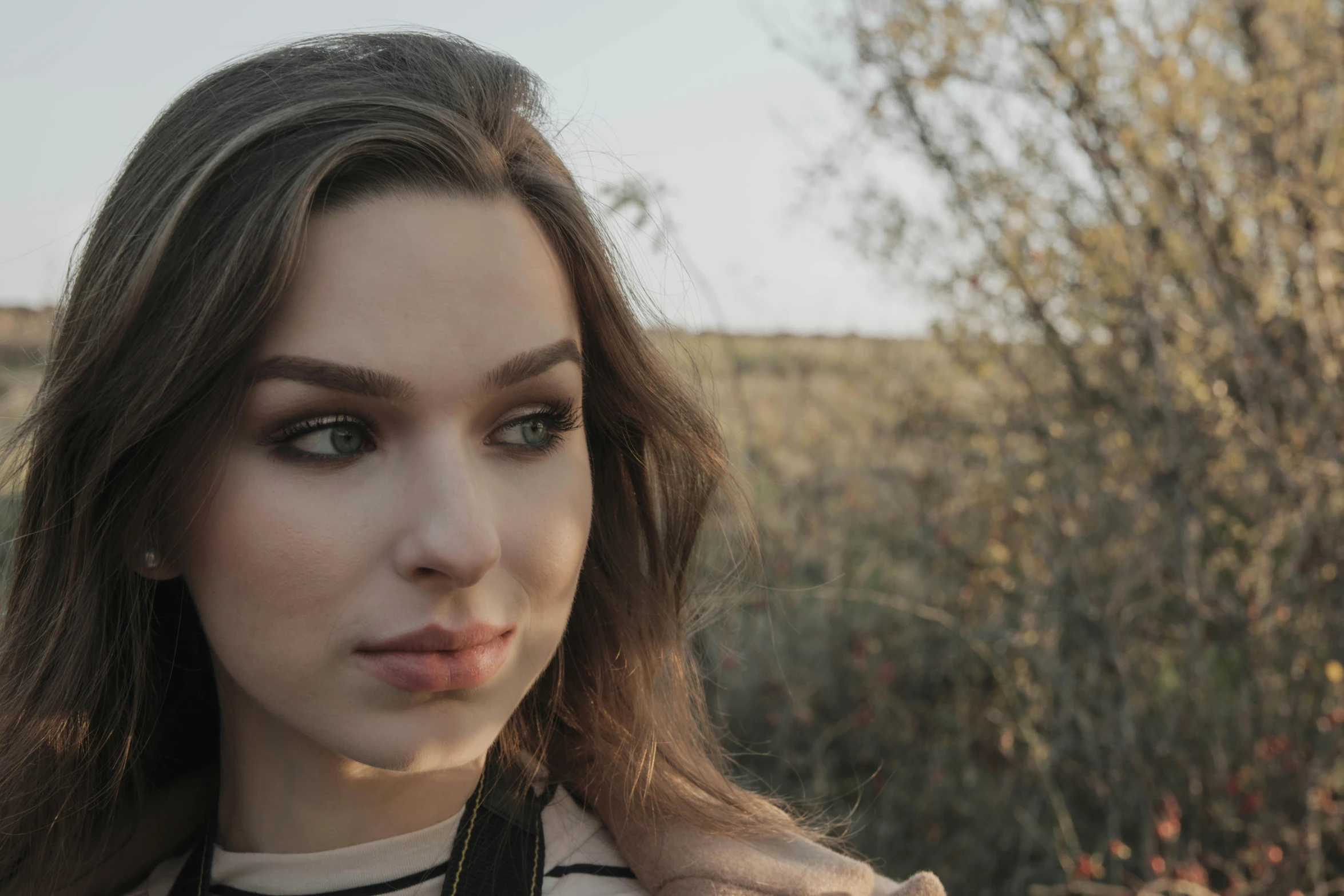 a woman posing for a picture in a field, trending on pexels, realism, big cheekbones, soft light.4k, portrait sophie mudd, cinematic shot ar 9:16 -n 6 -g