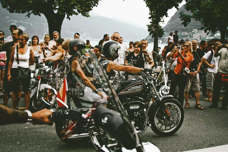 a man riding on the back of a motorcycle next to a crowd of people, pexels contest winner, italian, harley queen, avatar image, hot summer day