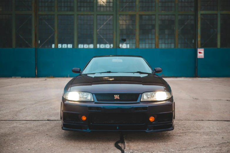 a black car is parked in a parking lot, a portrait, by Adam Rex, pexels contest winner, nissan gtr r 3 4, front view 2 0 0 0, square nose, russian and japanese mix