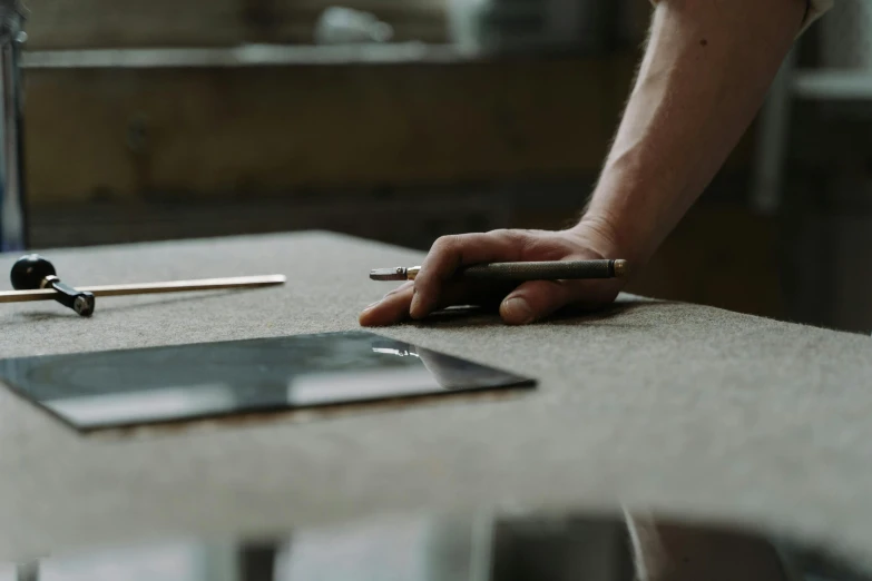 a tablet computer sitting on top of a table next to a person's hand, unsplash, process art, holding magical kitchen knives, granite, architect, looking at the ground