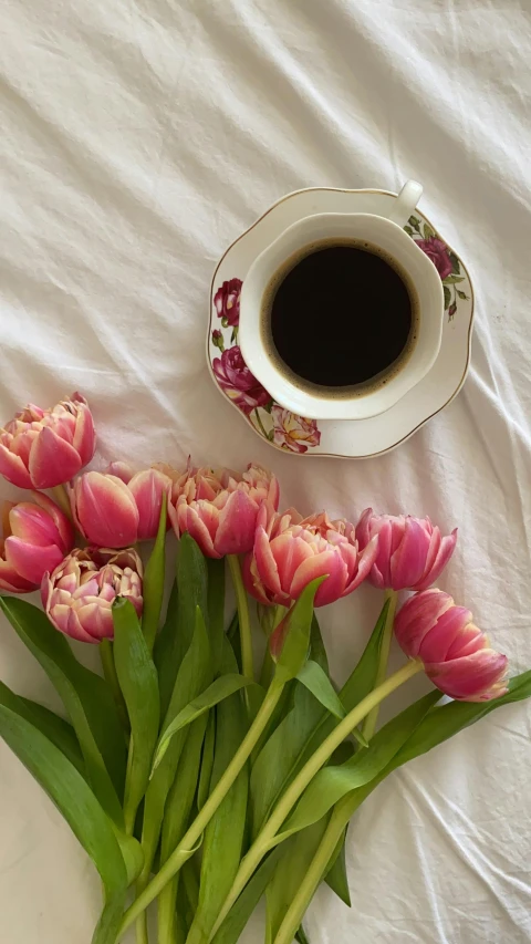 a bouquet of pink tulips next to a cup of coffee, by Lucia Peka, pexels contest winner, on my bed, cold brew coffee ), high quality photo, embroidered velvet