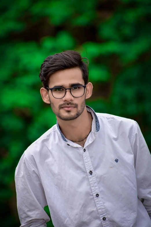 a man wearing glasses standing in front of a forest, by Rajesh Soni, cute young man, full frame image, multicoloured, portrait of a handsome