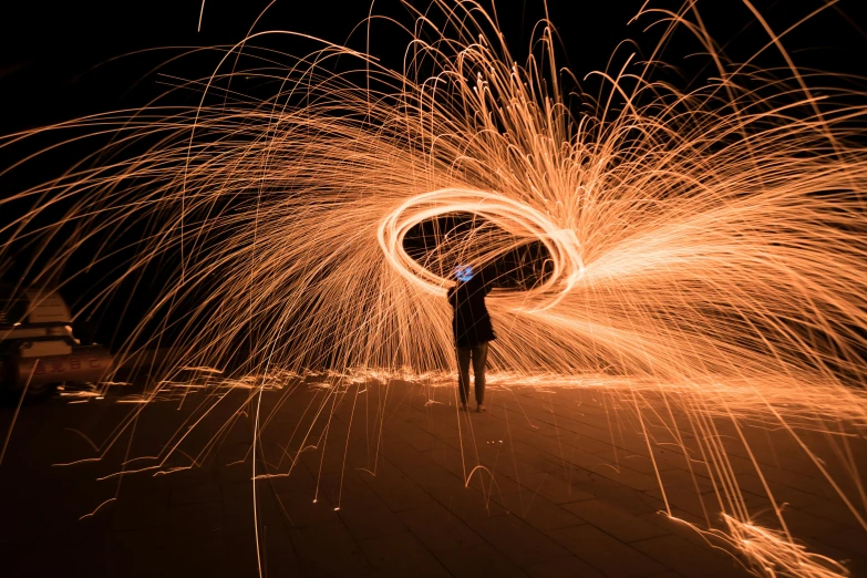 a man standing on top of a sandy beach holding a firework, pexels contest winner, art photography, orange halo, spiraling, outdoors at night, outline glow