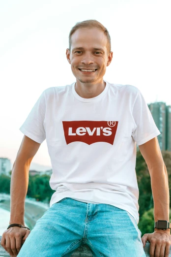a man sitting on a ledge wearing a levi's t - shirt, inspired by Louis Hersent, happening, volodymyr zelenskyy, rounded logo, lut, standing on a shelf