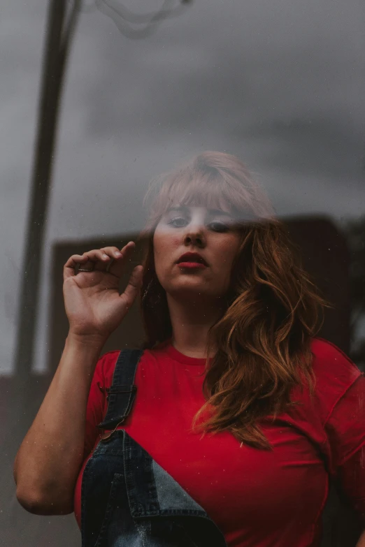 a woman in a red shirt smokes a cigarette, inspired by Elsa Bleda, pexels contest winner, ginger wavy hair, reflective windows, low quality photo, concert photo