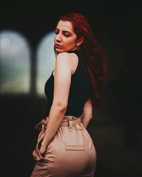 a woman in a black top and tan pants, inspired by Elsa Bleda, trending on pexels, renaissance, red head, low quality photo, dslr 5 0 mm portrait photo, leaked photo