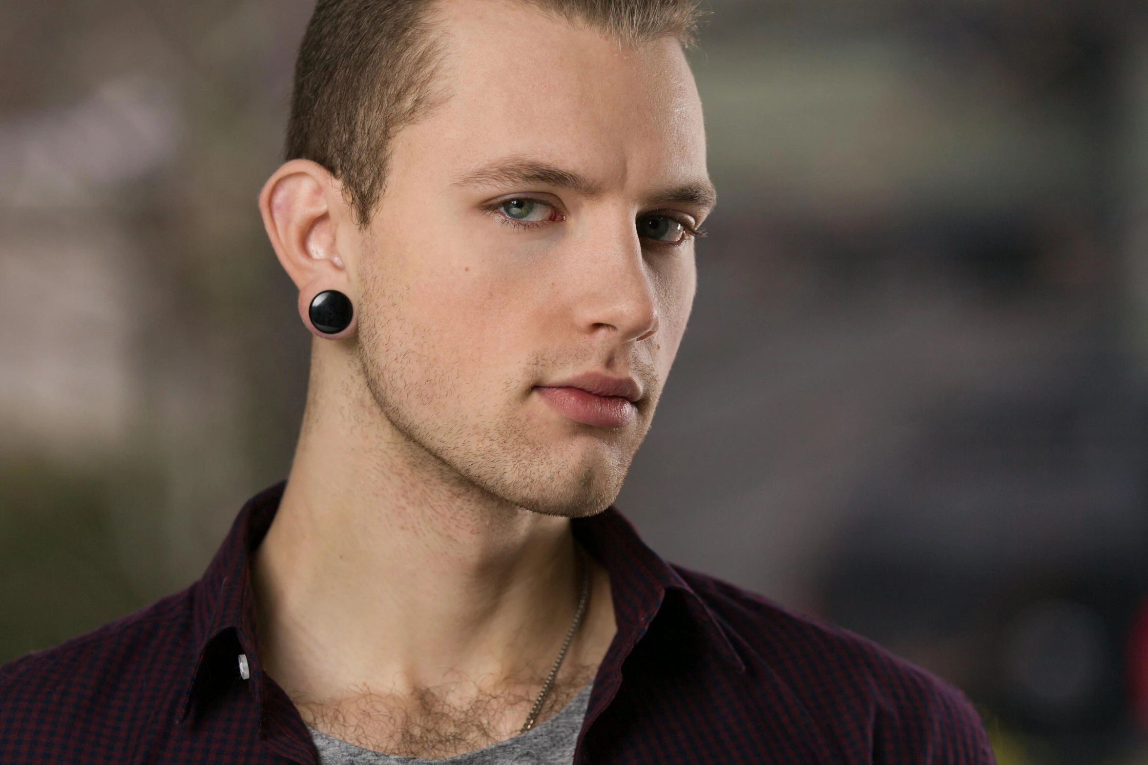 a close up of a person wearing ear plugs, a tattoo, inspired by Seb McKinnon, trending on pexels, photorealism, portrait of beautiful young man, wearing a black shirt, a handsome, artem