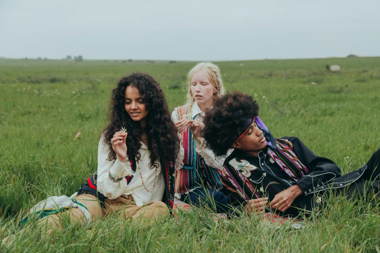 a group of women sitting on top of a lush green field, an album cover, by Emma Andijewska, trending on pexels, tribal clothing, kids playing, long afro hair, children playing with pogs