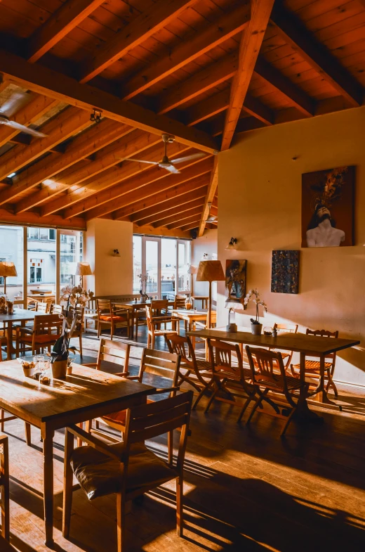 a dining room filled with lots of tables and chairs, a portrait, by Niko Henrichon, pexels, peaked wooden roofs, sun drenched, cafe interior, chilean