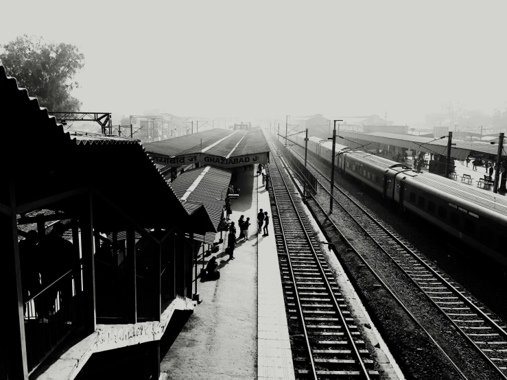 a black and white photo of a train station, a black and white photo, indore, fog!!!, the sun is shining. photographic, friends