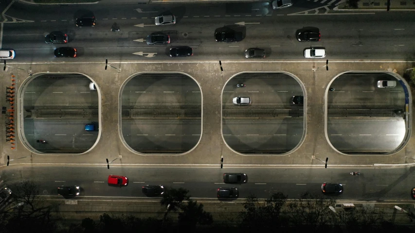 an aerial view of a parking lot at night, an album cover, by Alejandro Obregón, pexels contest winner, hyperrealism, overpass, portholes, symmetrical rim light, heavy traffic