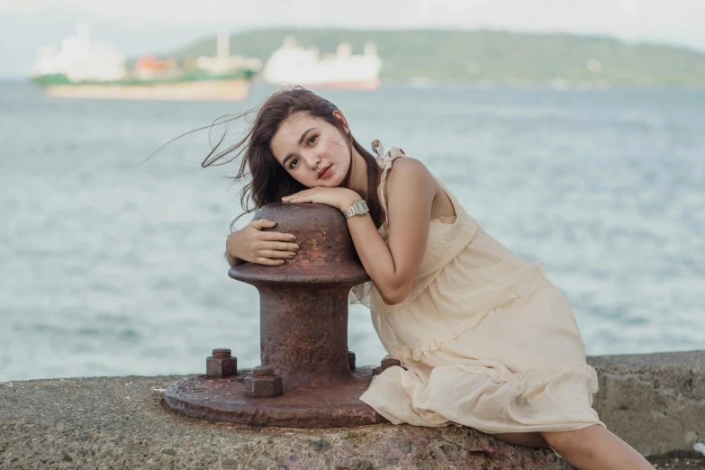 a woman in a dress leaning on a fire hydrant, inspired by Elsa Bleda, pexels contest winner, standing on a ship deck, fair olive skin, sitting on a rock, pretty face