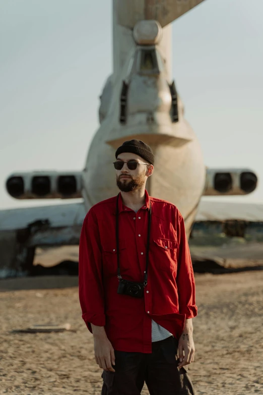 a man standing in front of an airplane, an album cover, pexels contest winner, wearing red clothes, yaroslav tokar, neckbeard, mars vacation photo