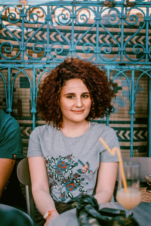 a man and a woman sitting at a table, an album cover, pexels contest winner, young middle eastern woman, curly and short top hair, portrait mode photo, blueish