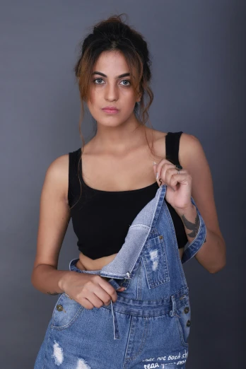 a beautiful young woman in a black top and denim overalls, by Robbie Trevino, indian super model, low quality photograph, croptop, trending on artisation