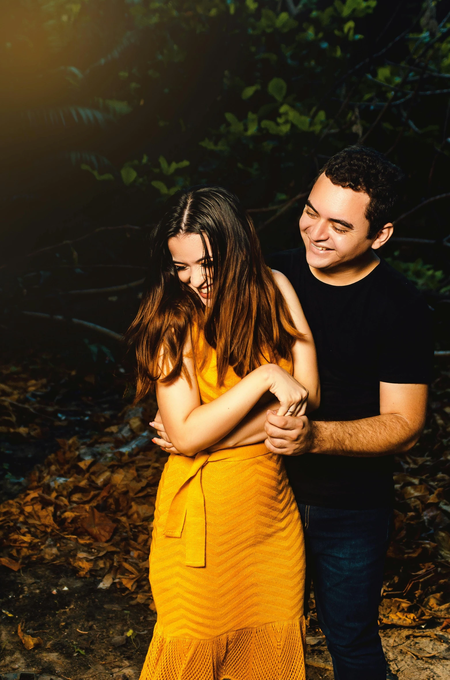 a man standing next to a woman in a yellow dress, a picture, pexels contest winner, man grabbing a womans waist, hispanic, warm glow, photograph captured in the woods