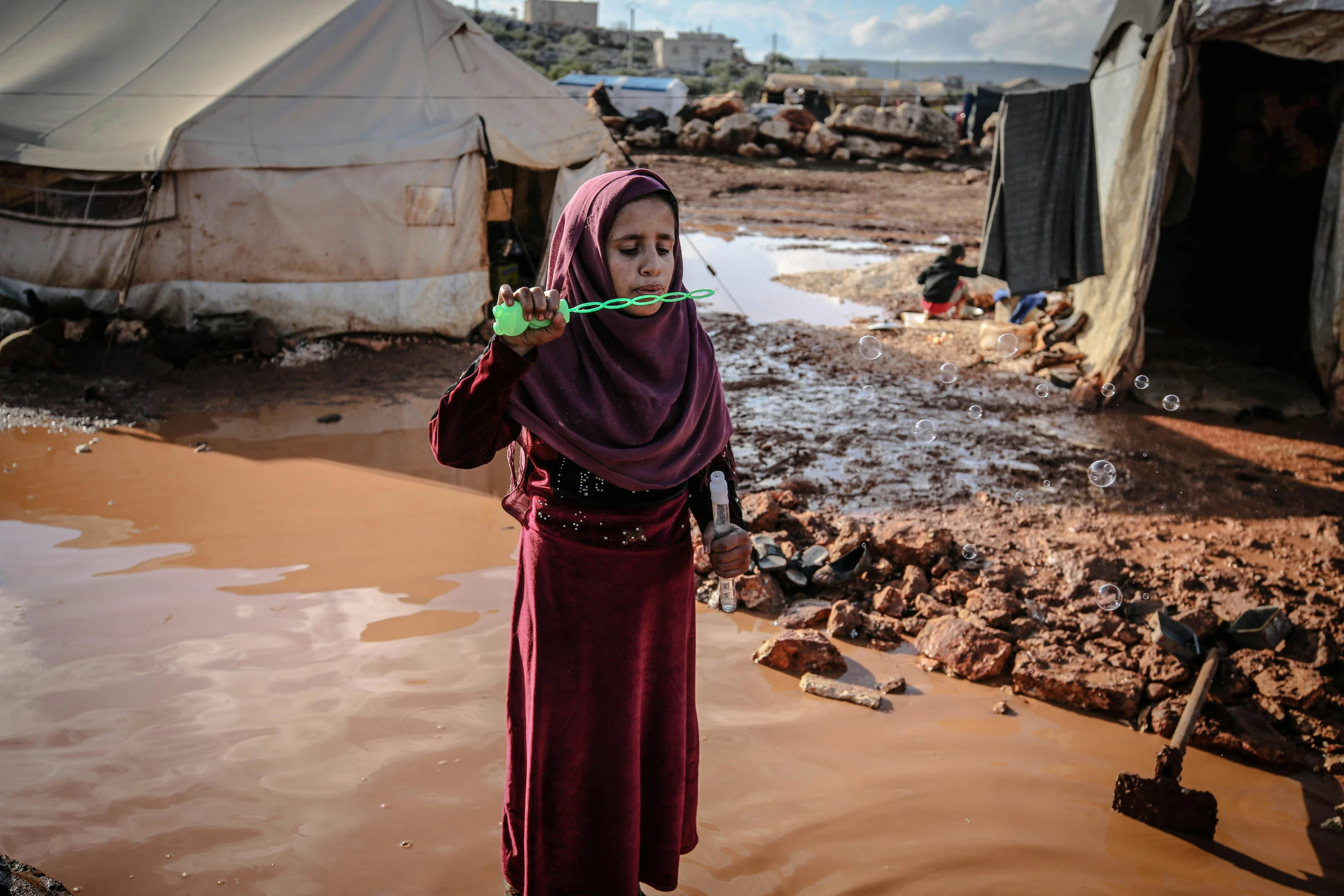 a woman standing in a muddy area holding a toothbrush, hurufiyya, drinking, multiple stories, settlement, covered