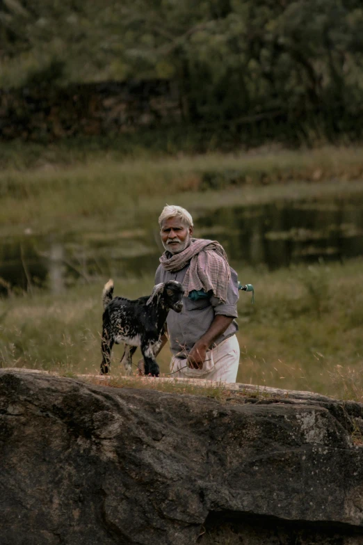 a man standing on top of a rock next to a dog, a picture, pexels contest winner, plein air, kerala village, a silver haired mad, picnic, zoomed in