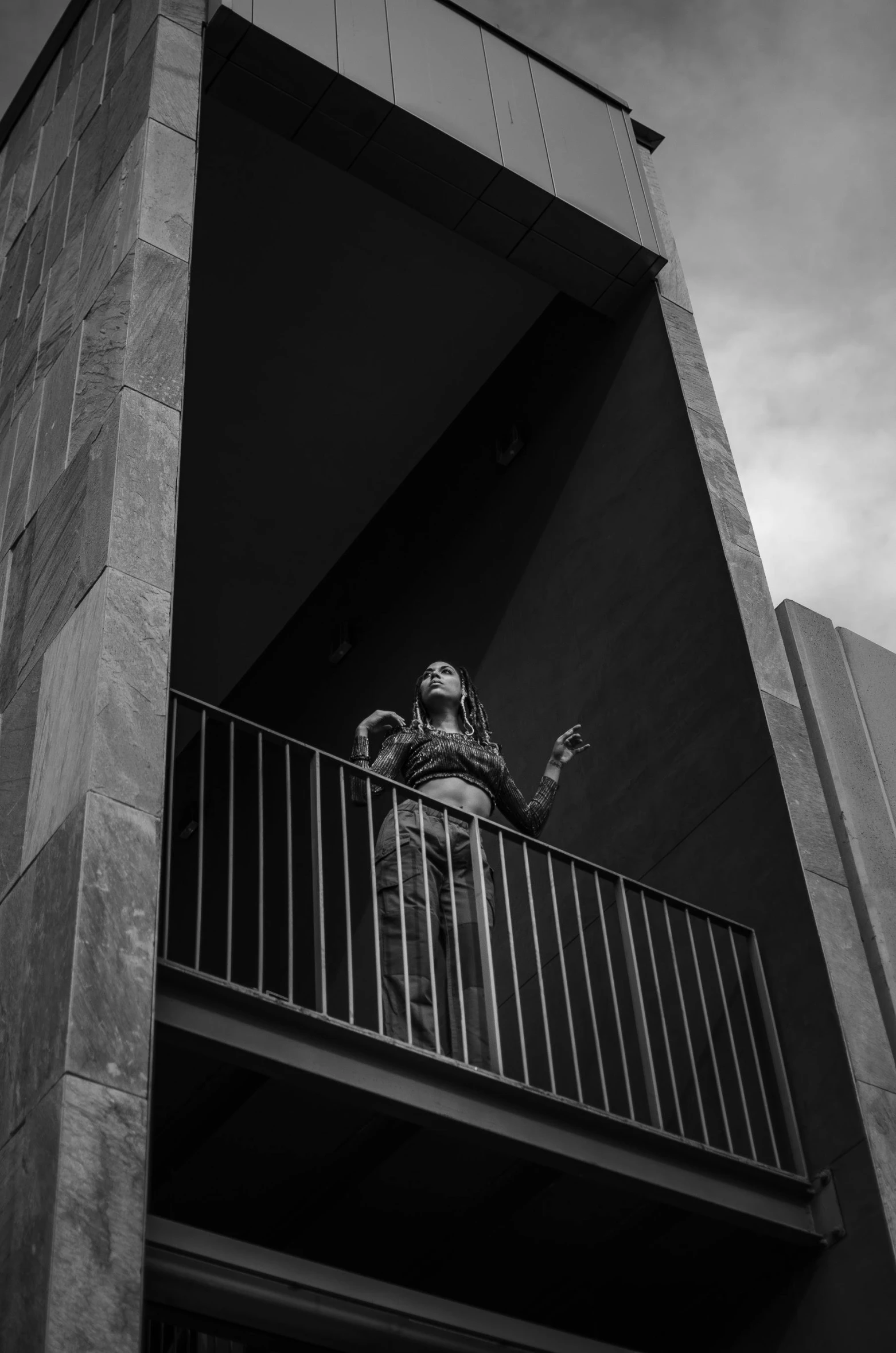 a black and white photo of a person on a balcony, unsplash, brutalism, dramatic smoking pose, female ascending into the sky, 2 4 mm iso 8 0 0 color, gothic aesthetic