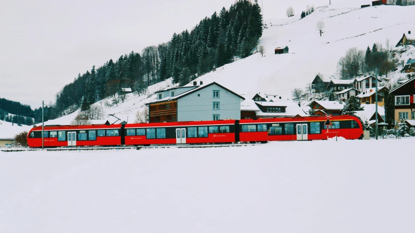 a large long red train on a steel track, by Julia Pishtar, pexels contest winner, alpine architecture, white snow, 🦩🪐🐞👩🏻🦳, white buildings with red roofs