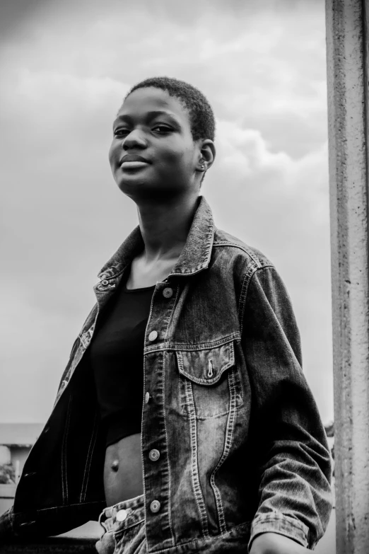 a black and white photo of a woman leaning against a pole, pexels contest winner, wearing a jeans jackets, emmanuel shiru, black teenage girl, androgynous face