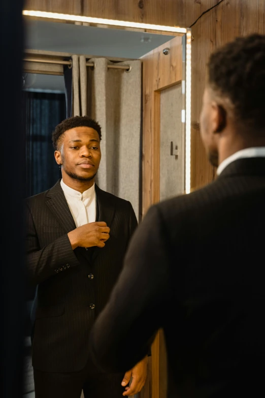 a man in a suit standing in front of a mirror, by Frank Mason, pexels contest winner, black teenage boy, facing each other, attractive young man, wearing a formal dress