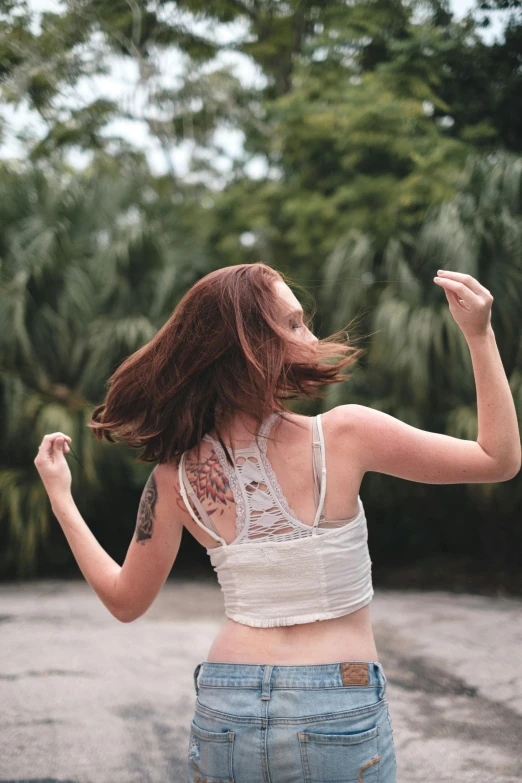 a woman riding a skateboard down a street, an album cover, inspired by Elizabeth Polunin, pexels contest winner, renaissance, in a white tank top singing, in a tropical forest, ( redhead, view from back