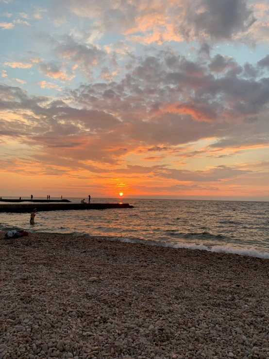 a bench sitting on top of a beach next to the ocean, during a sunset, profile image