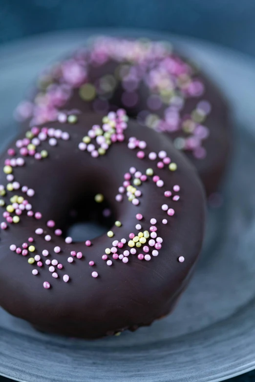 two chocolate donuts with sprinkles on a plate, by Jan Tengnagel, unsplash, black and purple, portrait photo, round format, soft