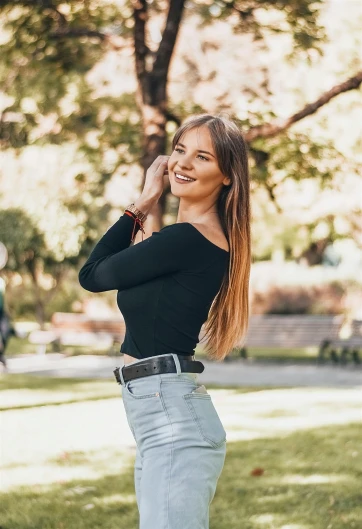a woman standing on top of a lush green field, wearing a black sweater, instagram influencer, with a bright smile, in a city park