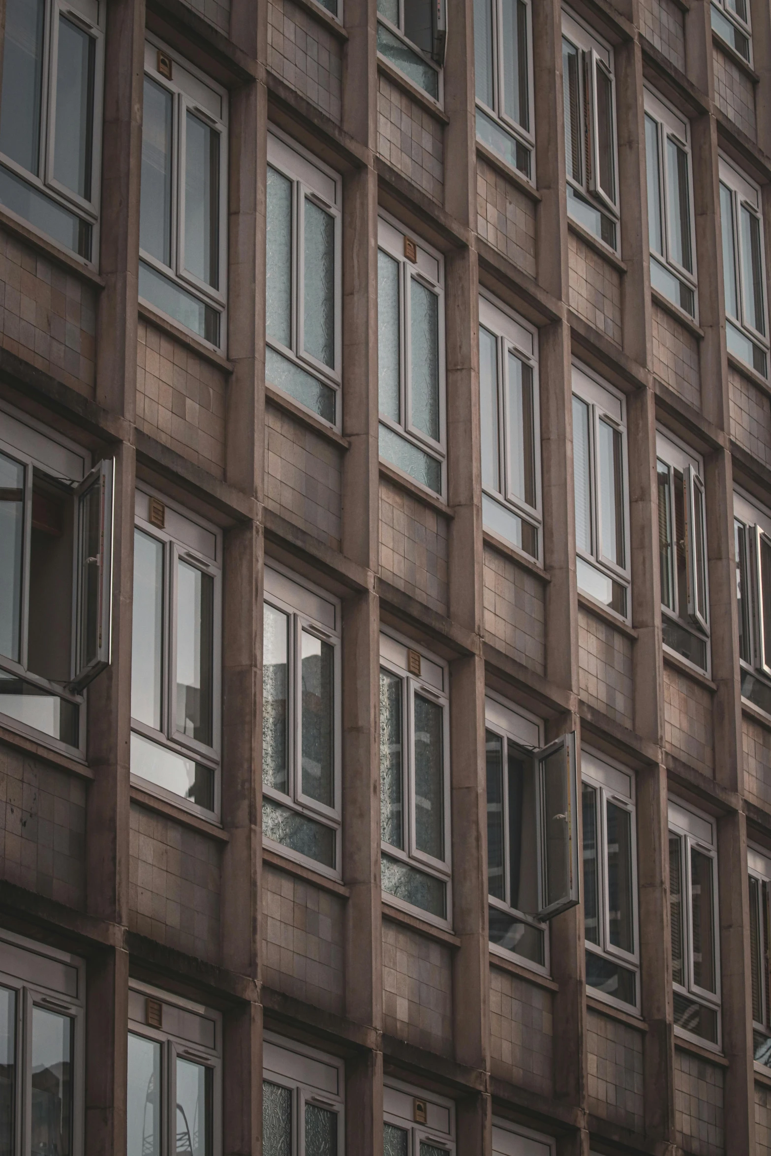 a tall brown building with lots of windows, pexels contest winner, brutalism, window ( city ), grey, low quality photo, candid