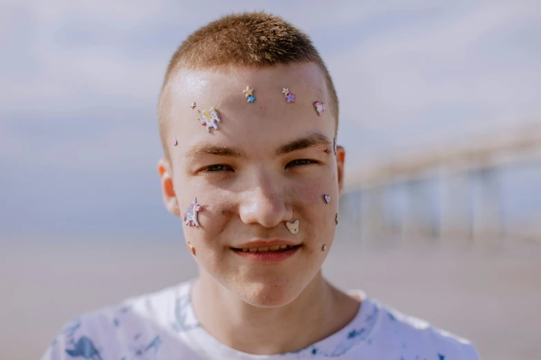 a young boy with sprinkles on his face, an album cover, by Attila Meszlenyi, trending on pexels, gemstone forehead, beachfront, shaved face, many stars