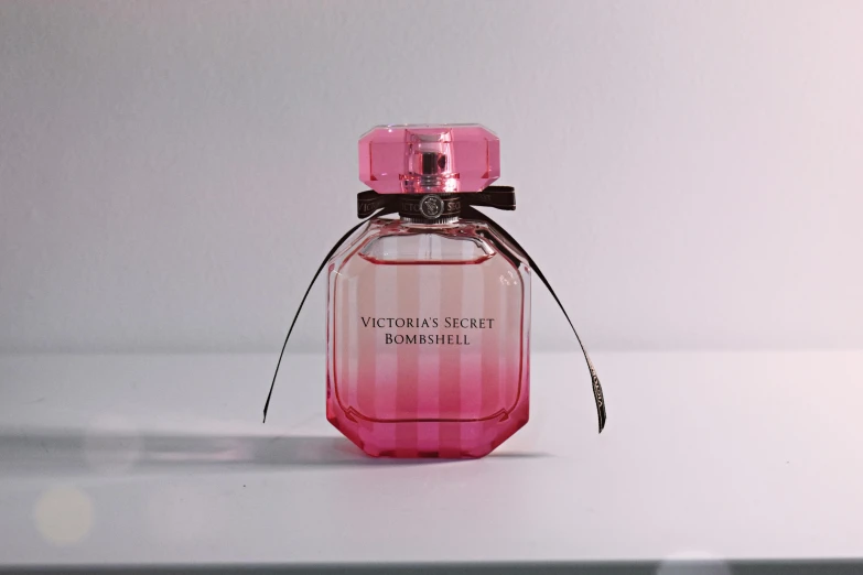 a pink bottle of perfume sitting on a table, victoria's secret, hexagonal shaped, detailed product shot, ((pink))