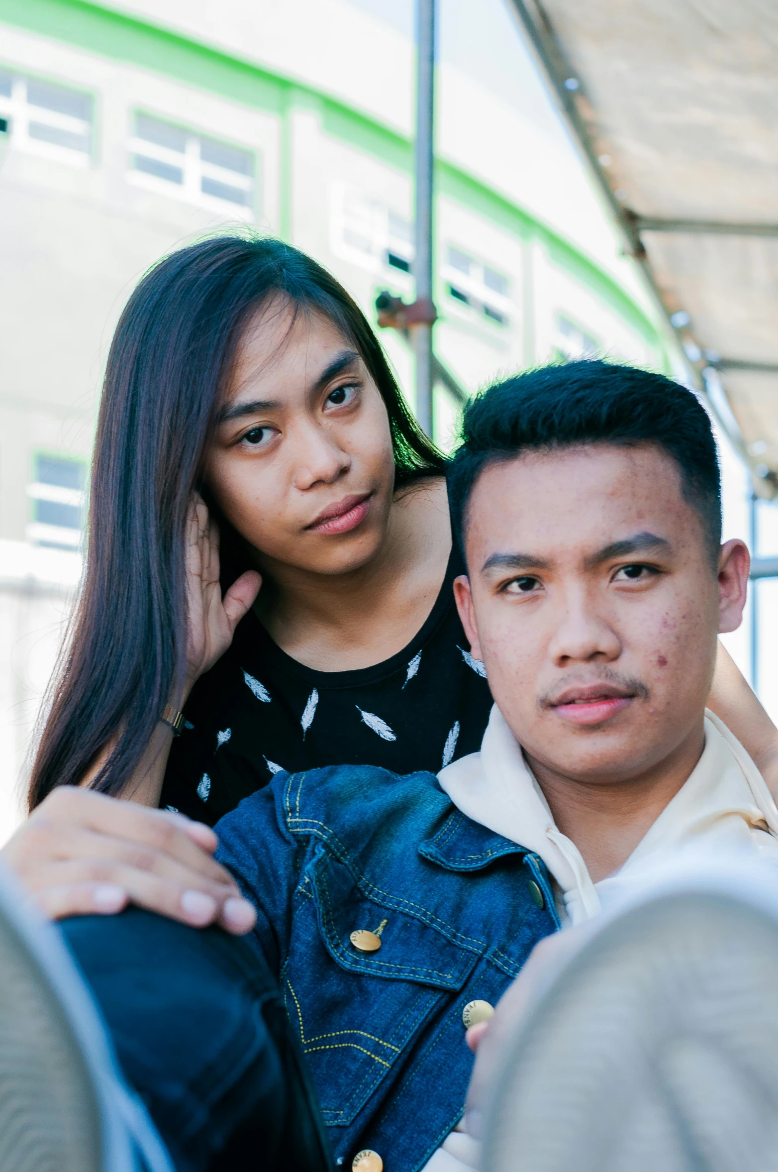 a man and a woman sitting next to each other, unsplash, realism, south east asian with round face, teenage boy, square, train far